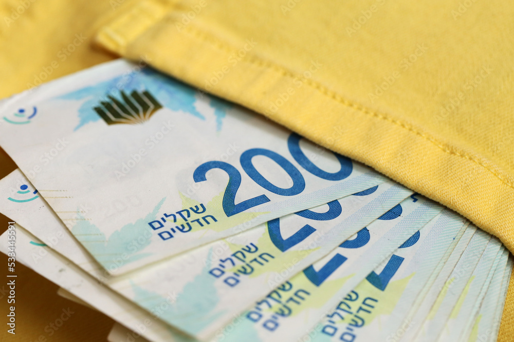Obraz premium in the pocket of yellow jeans is a pack of shekels in bills of two hundred