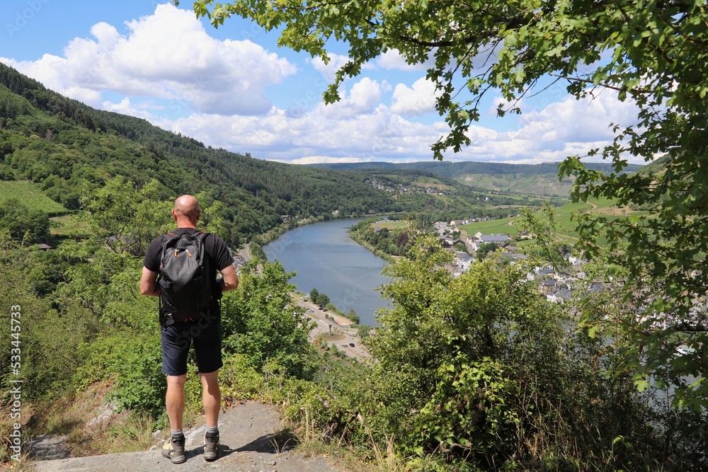 Male hiker on top of a mountain looking out over the river and town below