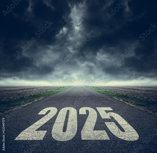 2025 written on highway road in the middle of asphalt road and dark cloudy sky. Future vision 2025