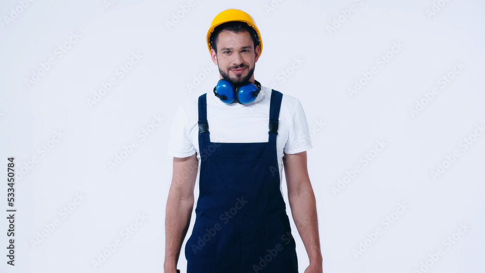young builder in overalls and hardhat smiling at camera isolated on white. young builder in overalls and hardhat smiling at camera isolated on white.