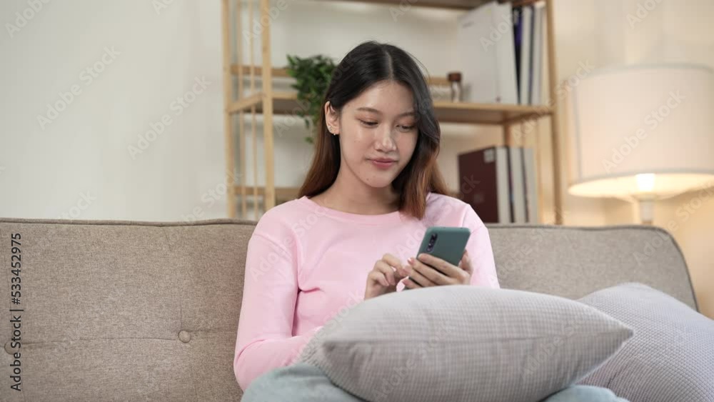 Young asian woman playing mobile games on sofa. Young asian woman playing mobile games on sofa.