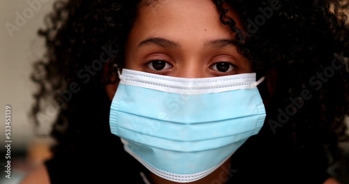 Black preteen girl putting covid-19 face mask prevention