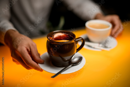 selective focus on male hand holding saucer with cup of tea