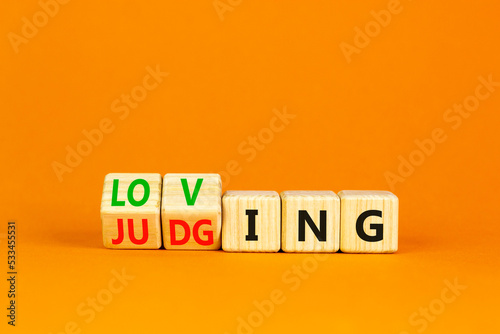Loving or judging symbol. Concept words Loving or Judging on wooden cubes. Beautiful orange table orange background. Business loving or judging concept. Copy space.