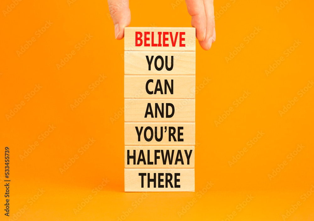 You can symbol. Concept words Believe you can and you are halfway there on wooden blocks on a beautiful orange table orange background. Businessman hand. Business motivational and you can concept.