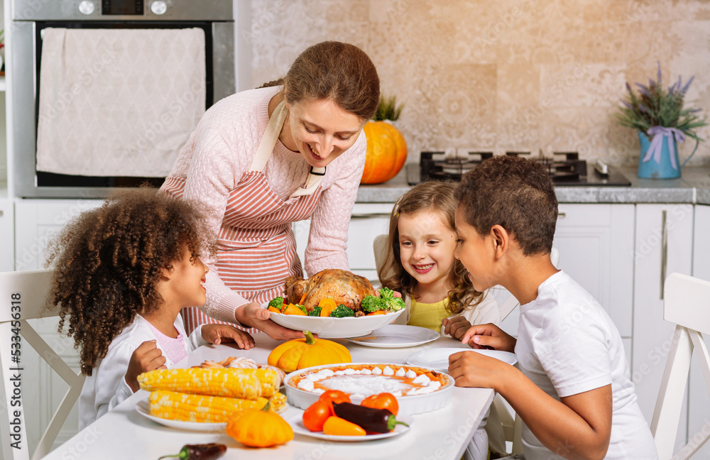 Joyful children at a festive Thanksgiving dinner. Serving a prepared festive dish on the table. Joyful children at a festive Thanksgiving dinner. Serving a prepared festive dish on the table.
