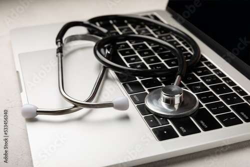 Laptop with stethoscope keyboard on gray texture background. Modern medical technologies. Software concept. Diagnostics and repair of computers and gadgets. Space for copy. Place for text.