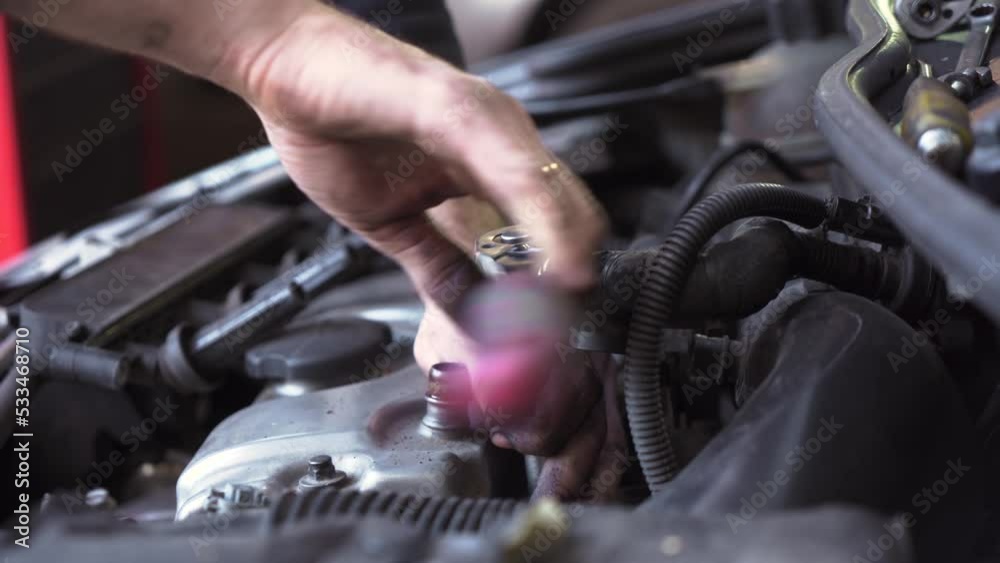 young auto mechanic repairs a car engine. spark plug replacement. young auto mechanic repairs a car engine. spark plug replacement.