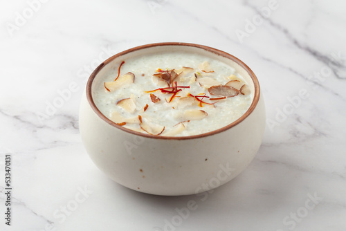 Close-up of Creamy Sabudana Kheer Garnished with saffron and dry fruits. Indian delicious dessert. Served in ceramic bowl. photo