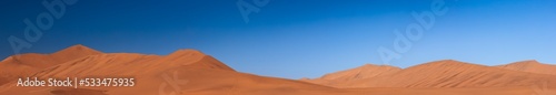 wide panorama of red dunes with blue sky at sossuvlei national park in Namibia, stunning wallpaper