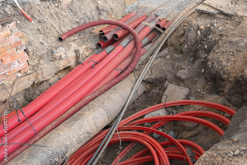 Network cables in red corrugated pipe are buried underground on the street. underground electric cable infrastructure installation. Construction site with A lot of communication Cables