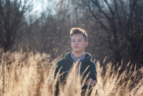 Sad teen boy sweatshirt on fall nature in aunumn day. Teenager is immersed in his thoughts and reflections. Teenagerhood. photo