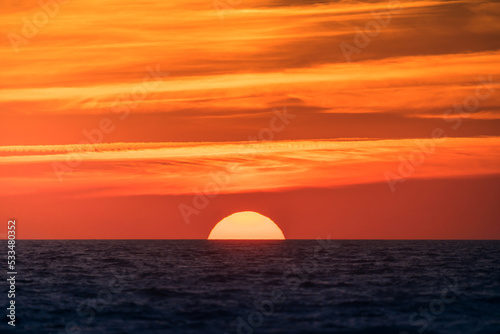 Bright sun setting above dark sea photo