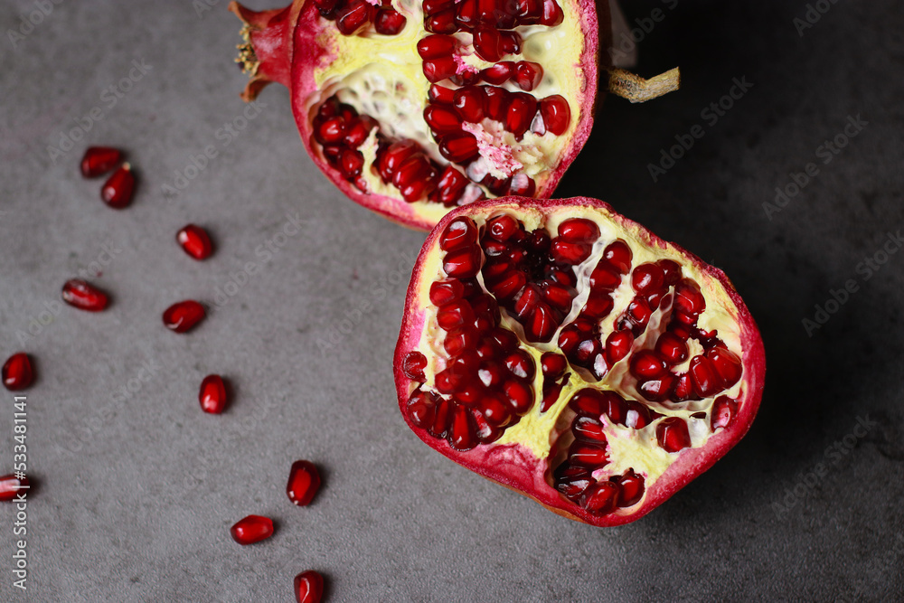 close up of a cut pomegranate on grey table, flat lay close up of a cut pomegranate on grey table, flat lay