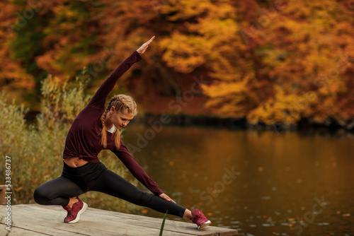 A young beautiful woman is doing sports in the autumn forest