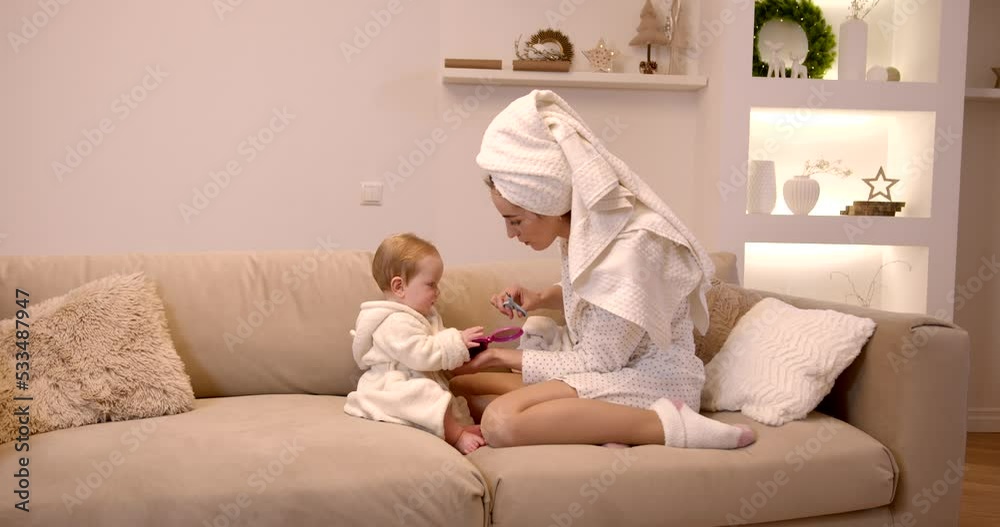 Young mother with baby sitting on sofa doing self care Young mother with baby sitting on sofa doing self care