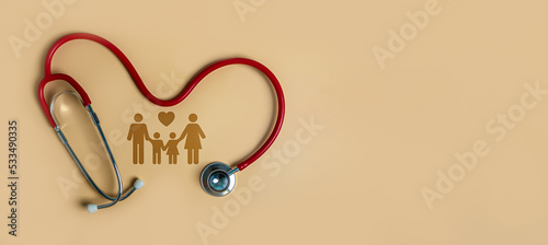 Top view of medical stethoscope and icon family on light orange background. Family health care insurance concept.
