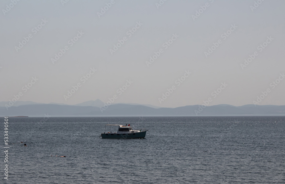 View of a yacht, Aegean sea and landscape captured in Ayvalik area of Turkey. It is a sunny summer day.