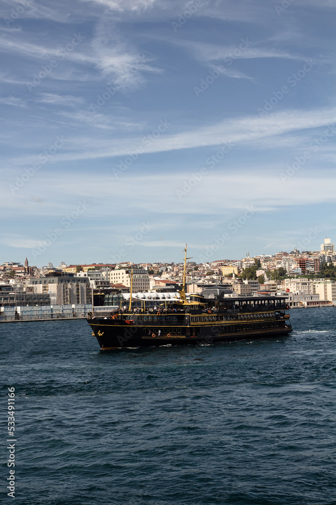 View of a traditional tour boat on Bosphorus in Istanbul. European side is in the view. It is a sunny summer day.