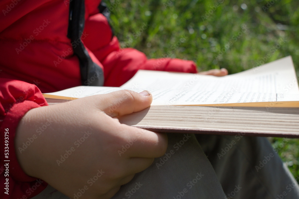 Obraz premium Child reading a classic book on a sunny fall day on a grassy hill in the country enjoying fine literature