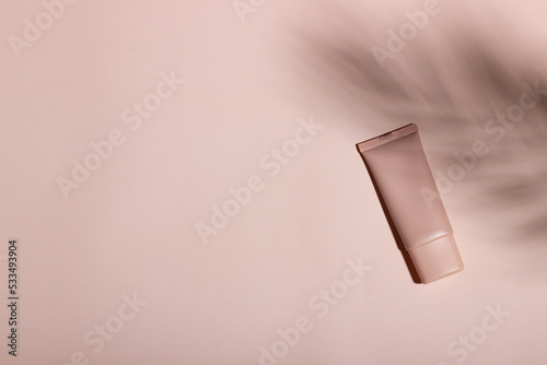 Schilderij op canvas Cosmetic cream or mask in a white tube with hard shadows from the leaves on a white background