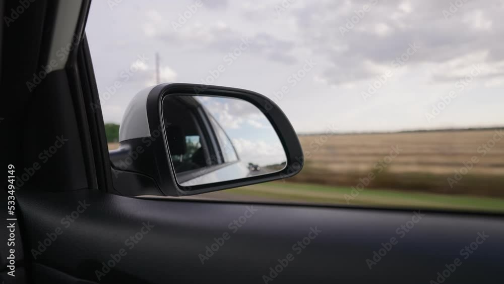 View from of the Side Mirror the Inside of a Driving Car Along the Highway in a Sunny Day. Concept of Vehicles and Transport. No People. View from of the Side Mirror the Inside of a Driving Car Along the Highway in a Sunny Day. Concept of Vehicles and Transport. No People.