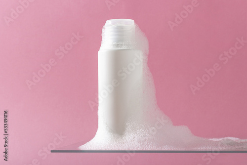 Cosmetics for face, body and hair care. Moisturizer, shampoo or facial cleanser on pink background with foam