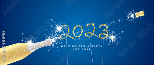 We wish you Happy New Year 2023 eve. Handwritten typography golden glitter stars white sparkler fireworks open champagne bottle on blue background. 2023 greeting card