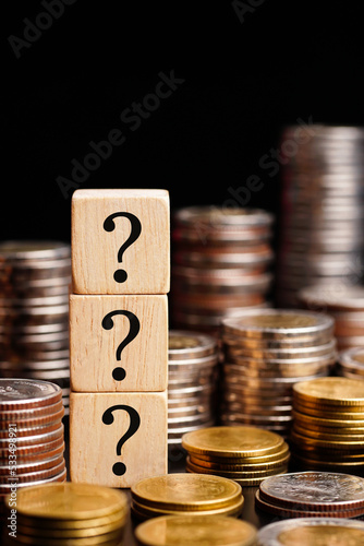 Wooden blocks with question marks with coins stacked, Money Insurance And Tax Question. vertical. 
