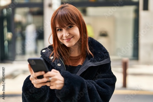 Young woman smiling confident using smartphone at street