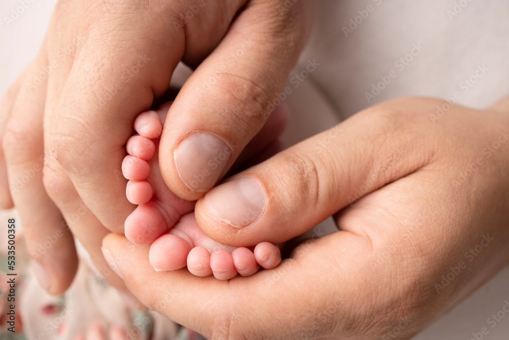 Mother and father are doing massage on her baby foot. Closeup baby feet in mother hands. Prevention of flat feet, development, muscle tone, dysplasia. Family, love, care, and health concepts. Mother and father are doing massage on her baby foot. Closeup baby feet in mother hands. Prevention of flat feet, development, muscle tone, dysplasia. Family, love, care, and health concepts.