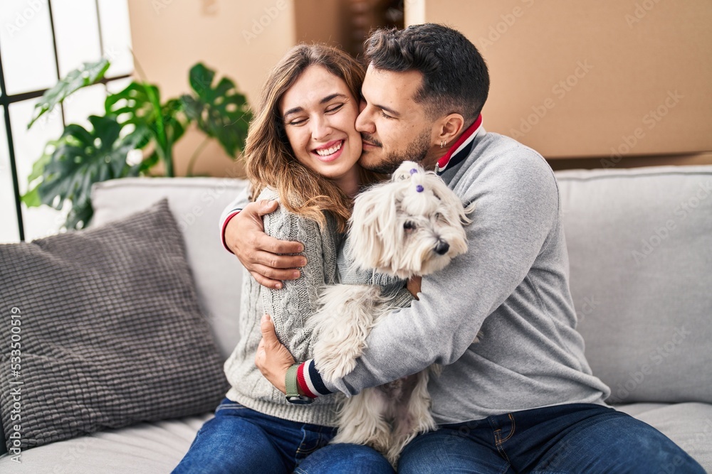 Man and woman smiling confident sitting on sofa with dog at new home Man and woman smiling confident sitting on sofa with dog at new home