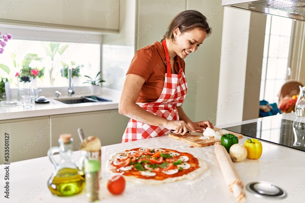 Young beautiful hispanic woman smiling confident cutting onion at the kitchen Young beautiful hispanic woman smiling confident cutting onion at the kitchen