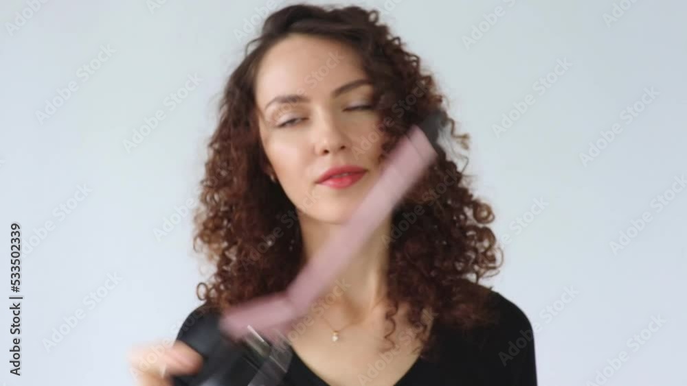 Curly hair. Beautiful smiling woman with curly hair, curls hair, uses curling iron tongs to get fine curls. Hair style and hairdressing tools. Curly hair. Beautiful smiling woman with curly hair, curls hair, uses curling iron tongs to get fine curls. Hair style and hairdressing tools.