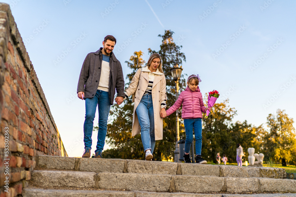 A happy three-member family walks and enjoys a beautiful winter day.