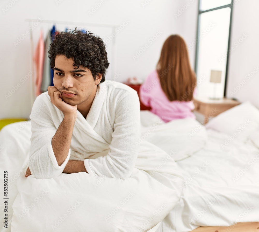 Young couple with serious expression on trouble sitting on the bed at bedroom. Young couple with serious expression on trouble sitting on the bed at bedroom.