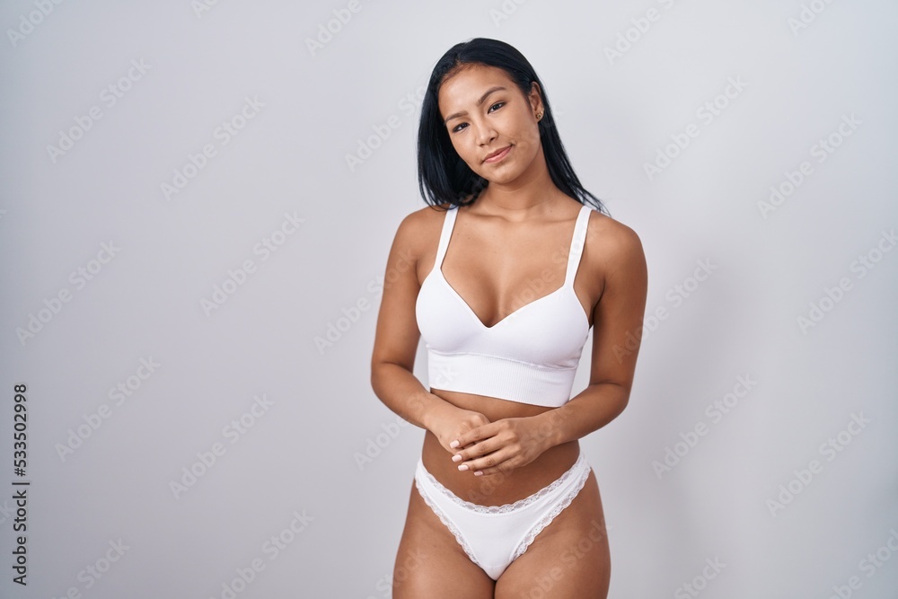 Hispanic woman wearing lingerie with hands together and crossed fingers smiling relaxed and cheerful. success and optimistic