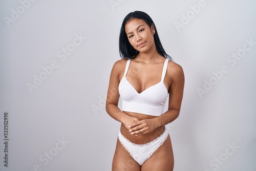 Hispanic woman wearing lingerie with hands together and crossed fingers smiling relaxed and cheerful. success and optimistic