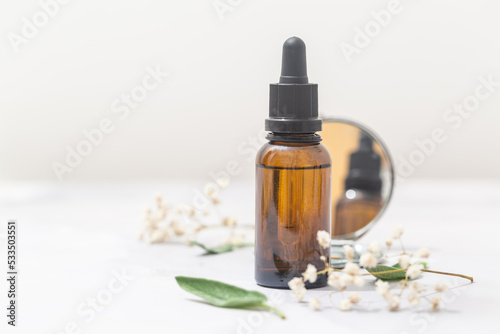 Flat lay composition with bottle of natural essential oil on white marble