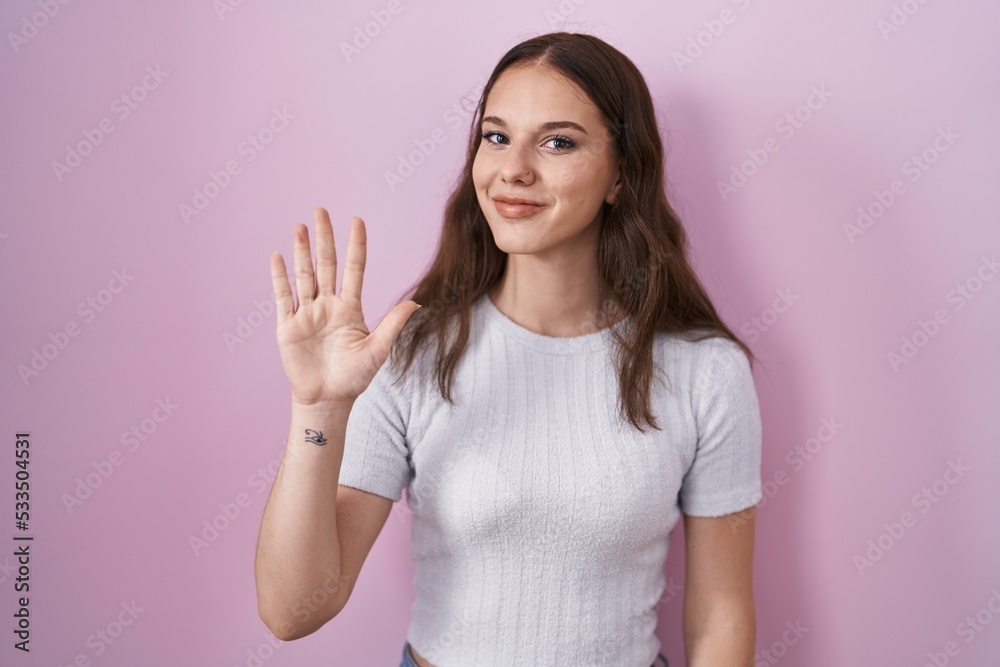 Young hispanic girl standing over pink background showing and pointing up with fingers number five while smiling confident and happy. Young hispanic girl standing over pink background showing and pointing up with fingers number five while smiling confident and happy.