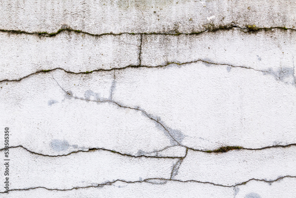 Obraz premium Textured grey white, concrete wall with heavy black cracks and grungy, rough painted, detail. Design element abstract background with holes, paint patches, scratches and weathering.