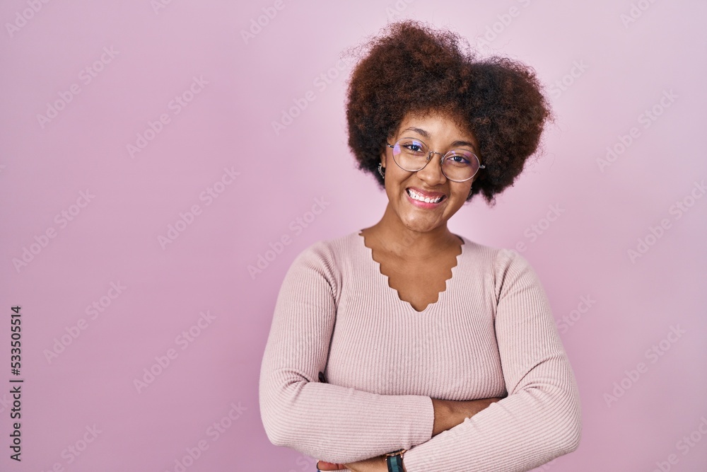 Young african american woman standing over pink background happy face smiling with crossed arms looking at the camera. positive person. Young african american woman standing over pink background happy face smiling with crossed arms looking at the camera. positive person.