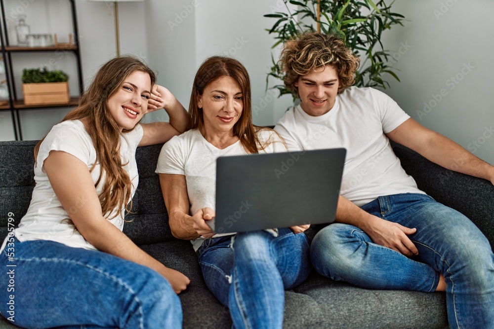 Mother and couple using laptop sitting on sofa at home