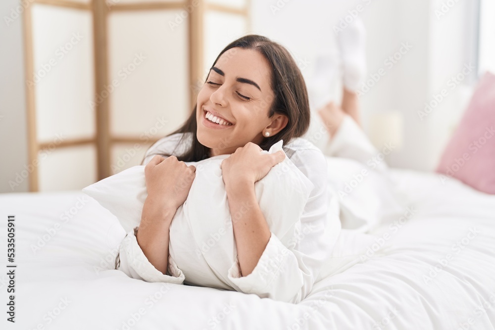 Young hispanic woman hugging pillow lying on bed at bedroom Young hispanic woman hugging pillow lying on bed at bedroom