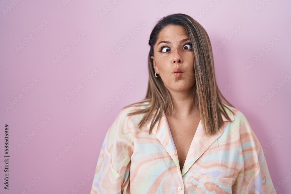 Blonde woman standing over pink background making fish face with lips, crazy and comical gesture. funny expression. Blonde woman standing over pink background making fish face with lips, crazy and comical gesture. funny expression.