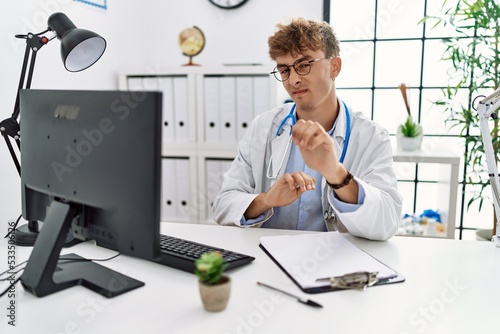 Young caucasian doctor man working at the clinic disgusted expression, displeased and fearful doing disgust face because aversion reaction. with hands raised