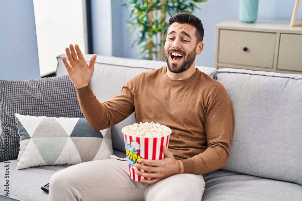 Young hispanic man watching movie sitting on sofa at home Young hispanic man watching movie sitting on sofa at home