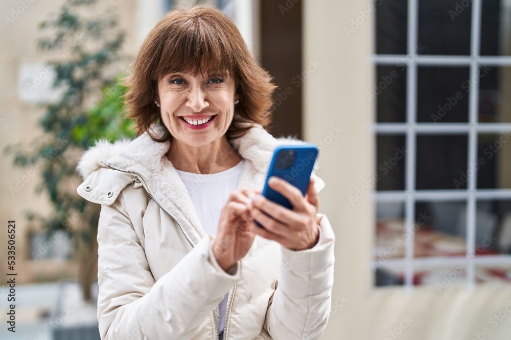 Middle age woman smiling confident using smartphone at coffee shop terrace Middle age woman smiling confident using smartphone at coffee shop terrace