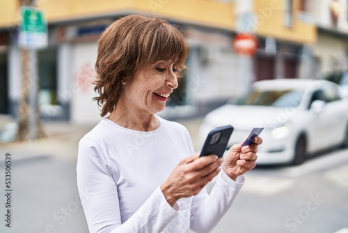 Middle age woman using smartphone and credit card at street Free Download Middle age woman using smartphone and credit card at street - GFXLoad