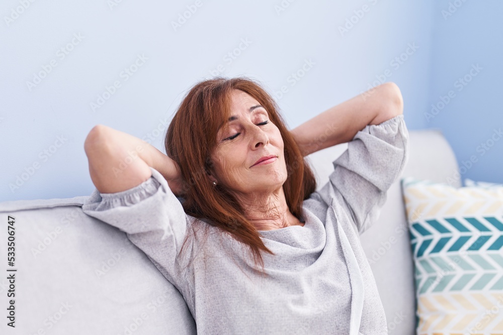 Middle age woman relaxed with hands on head sitting on sofa at home Middle age woman relaxed with hands on head sitting on sofa at home